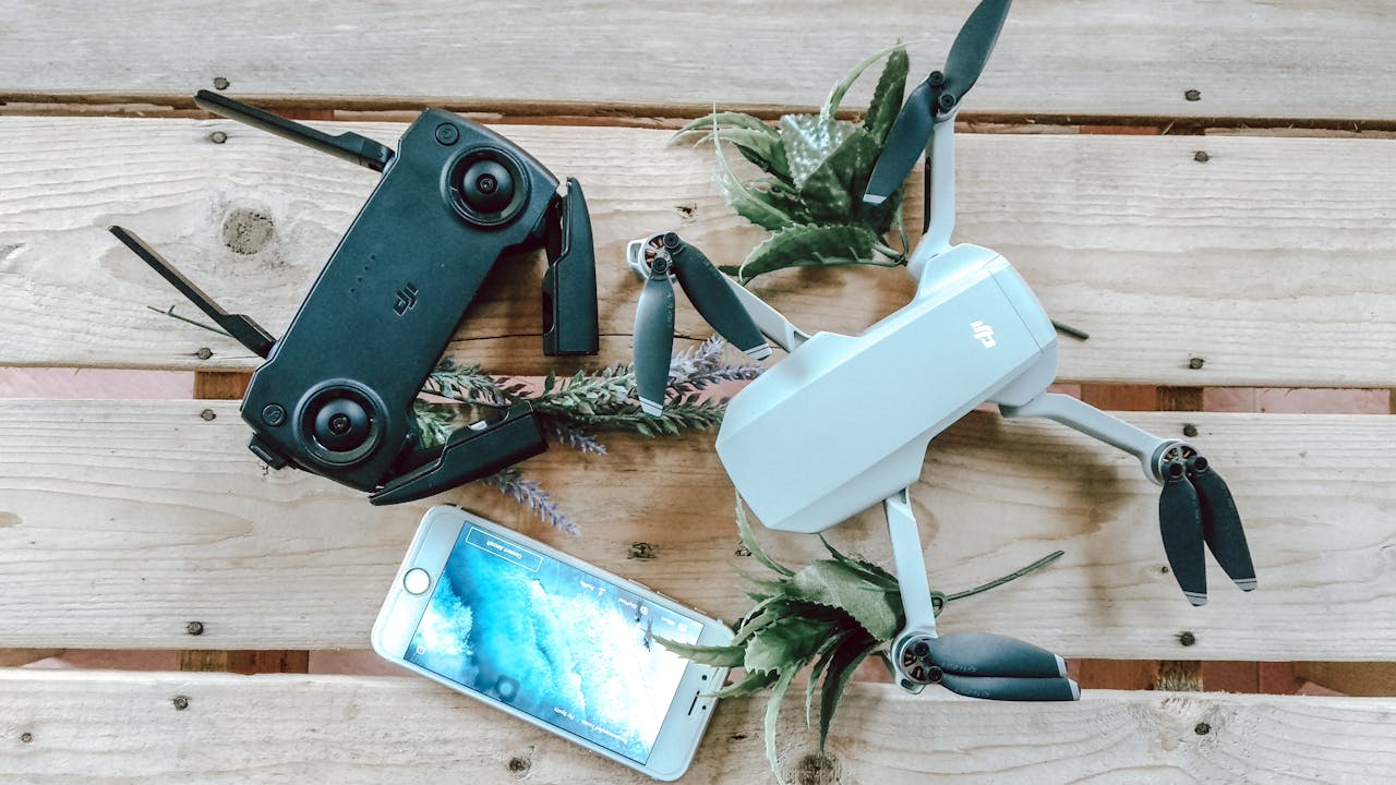 A flat lay of a drone, controller, and smartphone on a wooden surface.