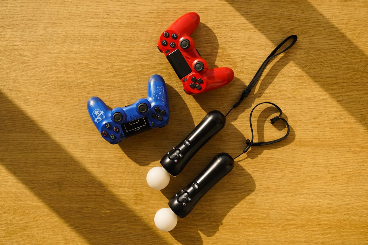 High angle view of gaming controllers on a sunlight-illuminated wooden table.